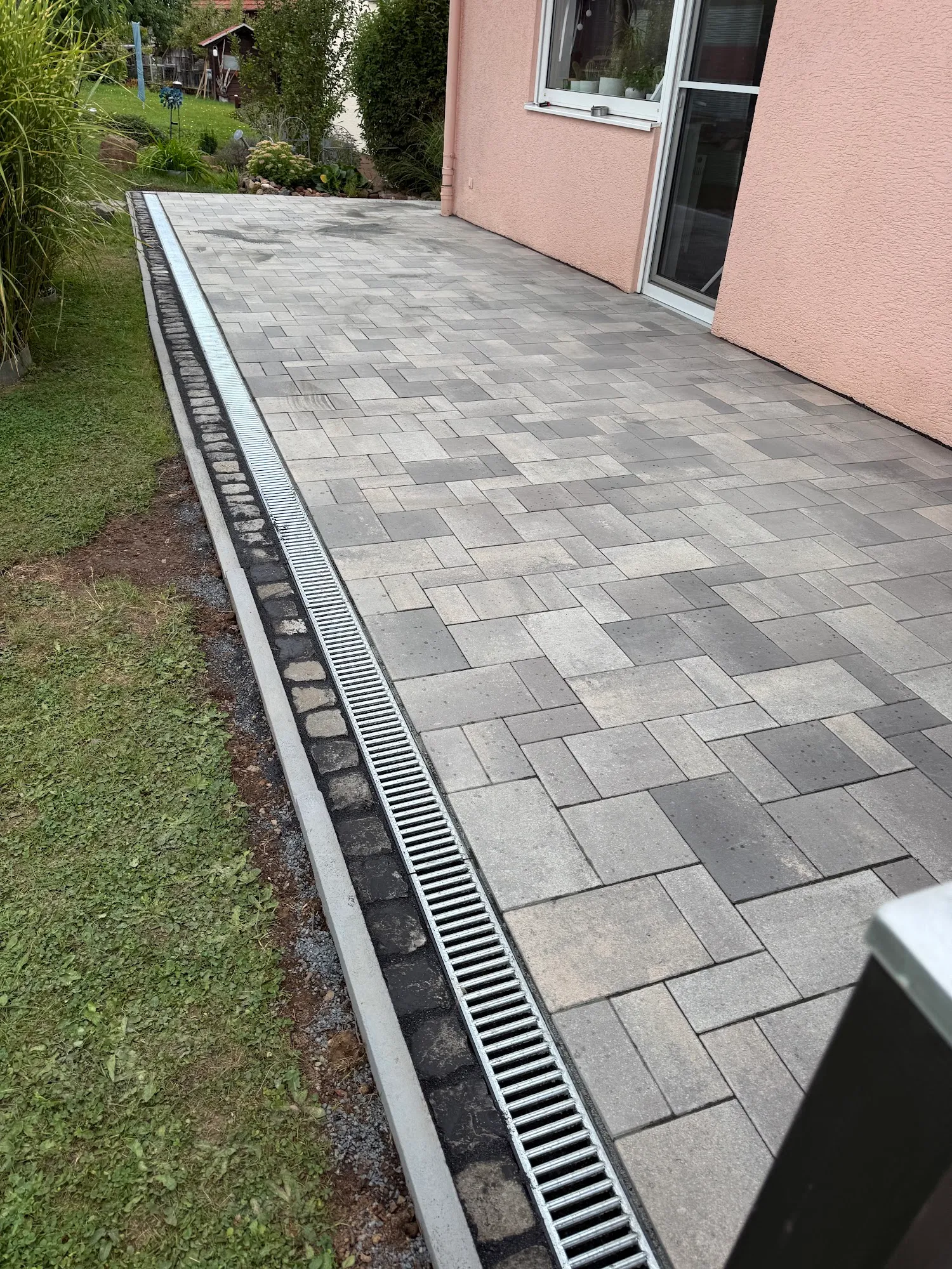 Fertiggestellte Gartenterrasse mit Drainagekanal und sauberer Kantenführung
