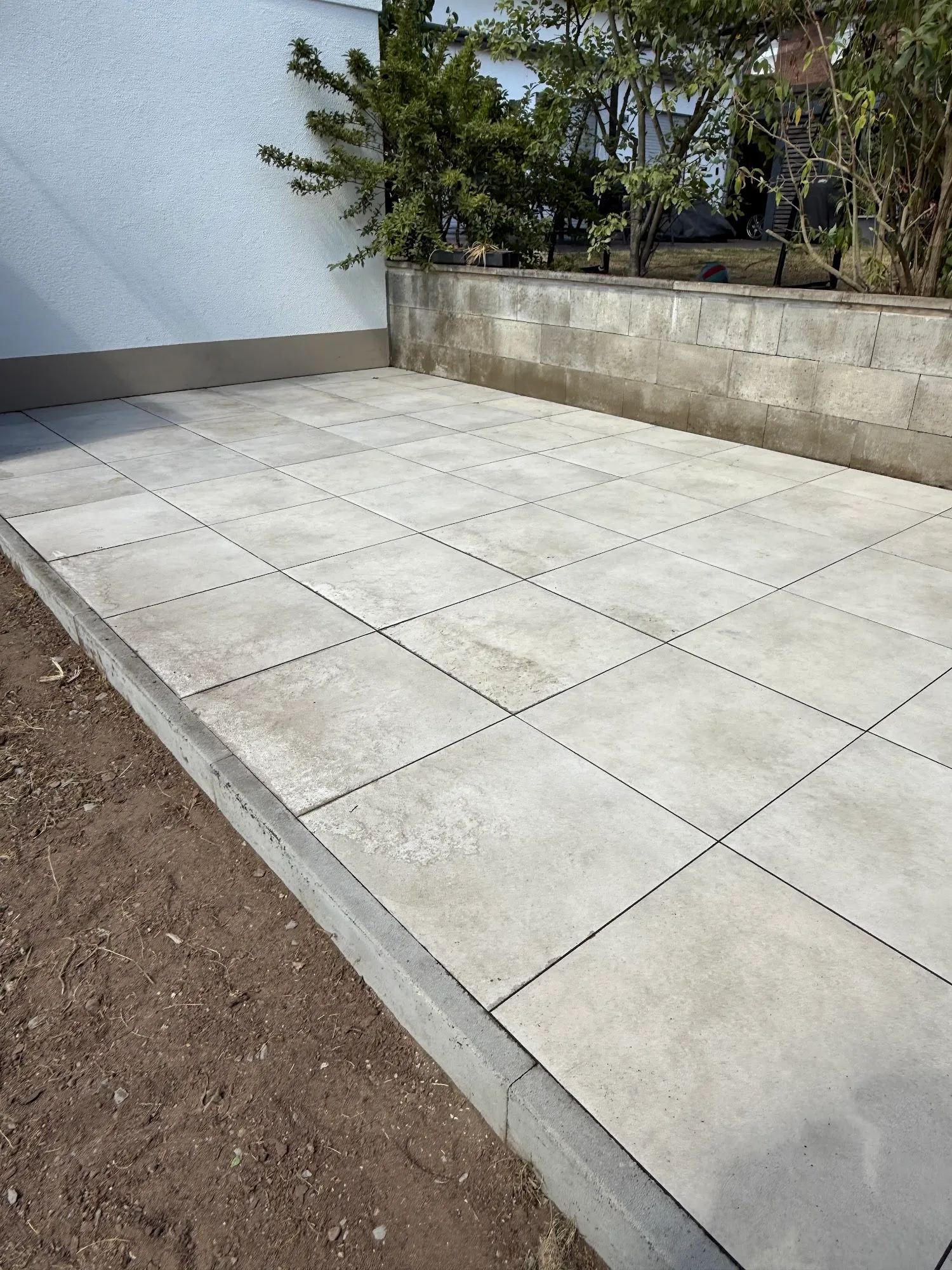 Fertig verlegte Terrasse aus großformatigen Platten mit sauberer Randeinfassung